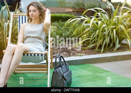 Woman sitting on a deck chair in an outdoor setting Stock Photo