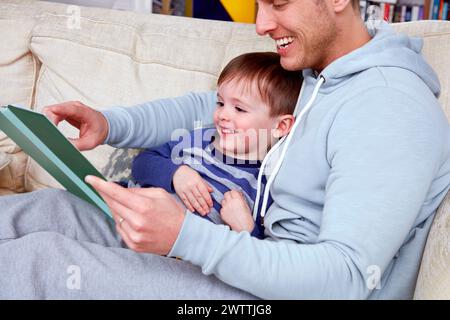 Man and child reading together on a couch Stock Photo