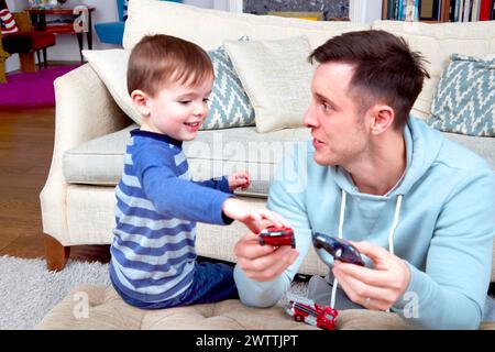 Father and son playing with toy cars on the floor. Stock Photo