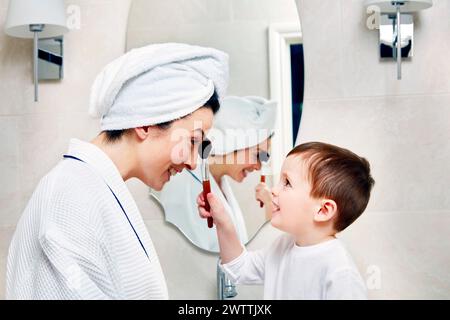 Woman and child in bathroom, woman applying makeup Stock Photo