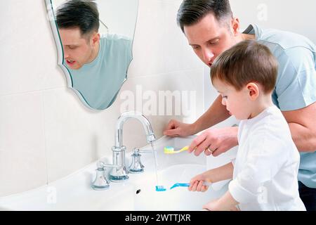 Man and child brushing teeth in bathroom Stock Photo