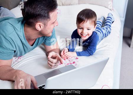 Father and son using laptop on bed Stock Photo