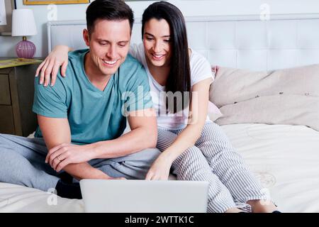 Couple using a laptop on a bed. Stock Photo