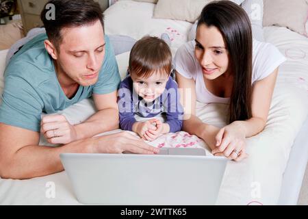 Family using a laptop on a bed. Stock Photo