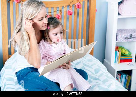 Adult reading to child in a cozy bedroom Stock Photo