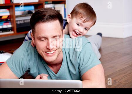 Man and child smiling while using a laptop together Stock Photo