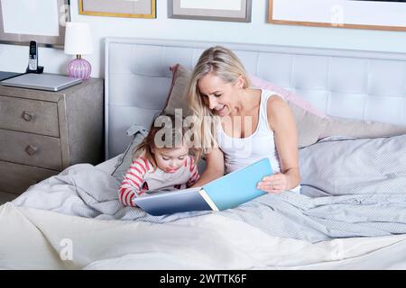 Woman and child reading a book in bed Stock Photo