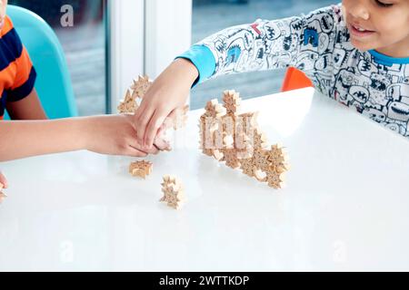 Children playing with puzzle pieces at a table. Stock Photo