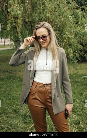 A woman wearing brown pants and a blazer. She stands confidently, showcasing a professional attire in a stylish ensemble. Stock Photo