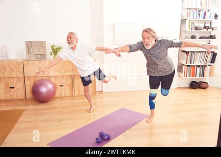 Two seniors practicing balance exercises indoors Stock Photo