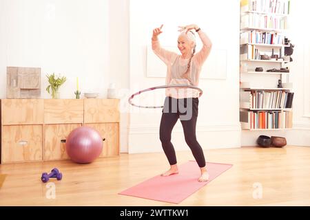 Senior woman exercising with a hula hoop at home Stock Photo
