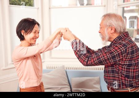 Two people smiling and holding hands indoors Stock Photo