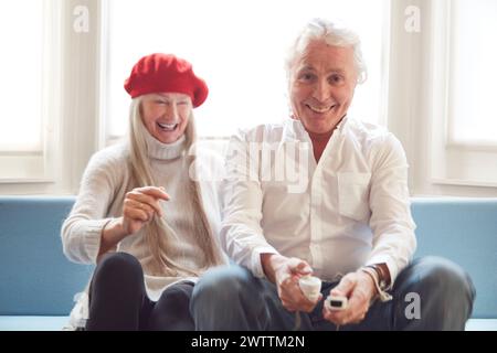 Smiling couple playing video games on a couch Stock Photo