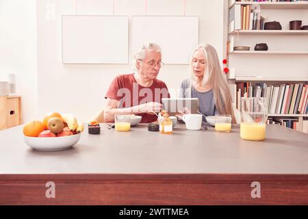Elderly couple having breakfast and looking at a tablet Stock Photo