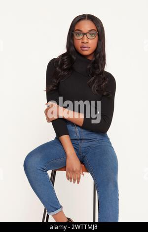 Woman sitting on stool in jeans and black top Stock Photo