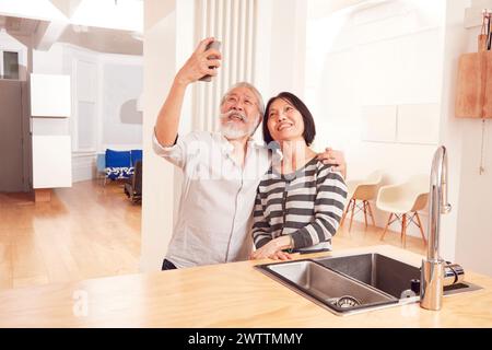 Elderly couple taking a selfie in kitchen Stock Photo