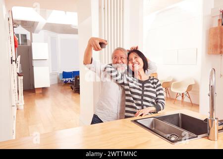Elderly couple taking a selfie in kitchen Stock Photo