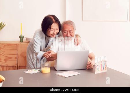 Elderly couple smiling and looking at a laptop Stock Photo