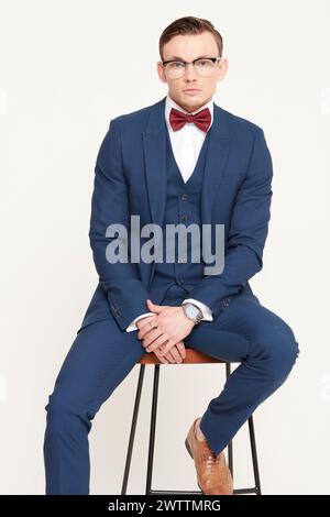 Man in a suit sitting on a stool Stock Photo