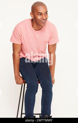 Man smiling while sitting on a stool Stock Photo