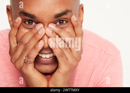 Man covering his face with hands, peeking through Stock Photo