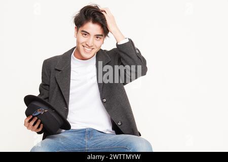 Smiling young man holding a hat Stock Photo