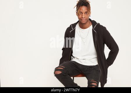 Young person sitting confidently in a studio setting Stock Photo