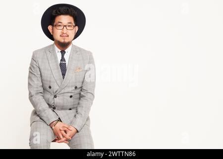 Man in a gray suit and black hat sitting Stock Photo
