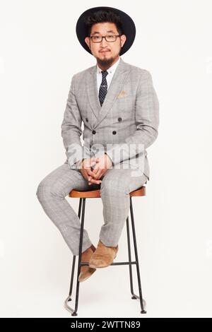 Man in a gray suit sitting on a stool Stock Photo