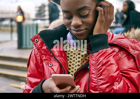 Woman using phone with headphones around neck Stock Photo
