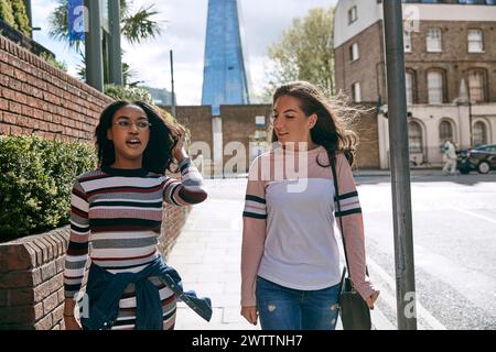 Two women walking and talking in an urban setting Stock Photo