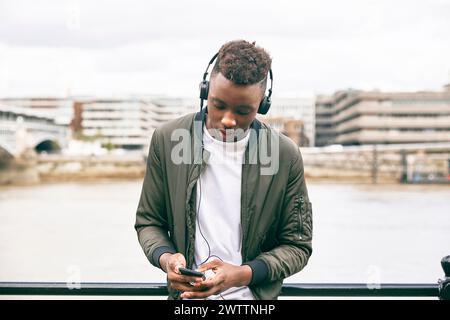 Man with headphones using smartphone near a river Stock Photo