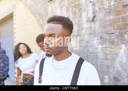 Young man walking in urban setting with friends in background Stock Photo