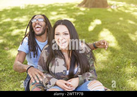 Joyful couple sitting on grass in a park Stock Photo