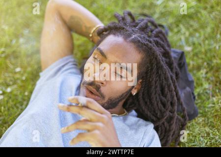 Man relaxing in grass with a thoughtful expression. Stock Photo
