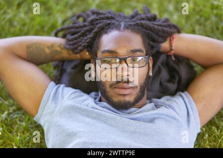 Man relaxing on grass with hands behind head Stock Photo