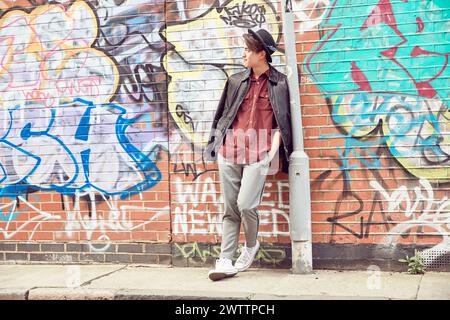Man leaning against a wall with graffiti Stock Photo