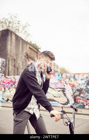 Man talking on the phone while holding a bike Stock Photo