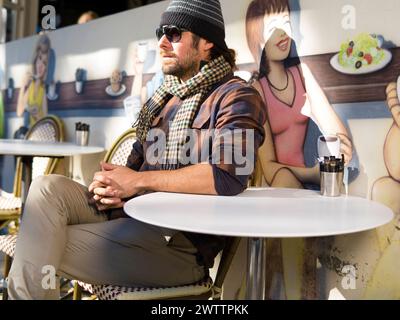 Man sitting at a cafe with mural in the background Stock Photo