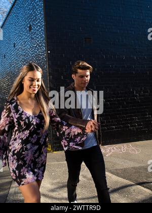 Couple walking by a blue wall in sunlight Stock Photo