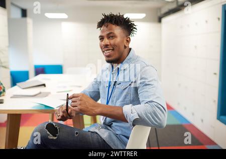 Smiling man sitting in a colorful office space Stock Photo