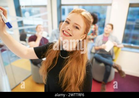 Young woman writing on whiteboard in a meeting room Stock Photo