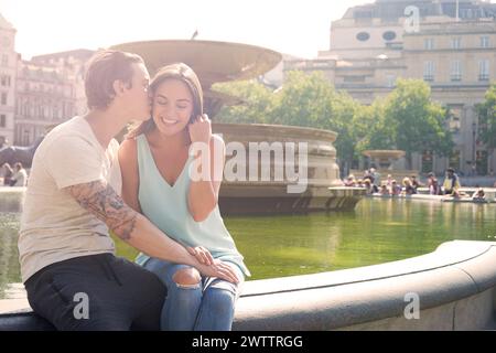 Couple kissing by a fountain in a sunny park Stock Photo