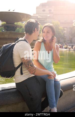 Couple sitting and interacting near a fountain Stock Photo