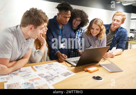Team collaborating over a laptop in an office Stock Photo
