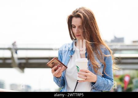Woman with coffee using smartphone outdoor Stock Photo