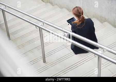 Woman sitting on stairs using a tablet Stock Photo