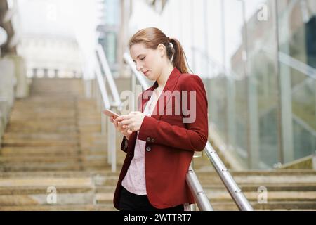 Woman using phone on city stairs Stock Photo