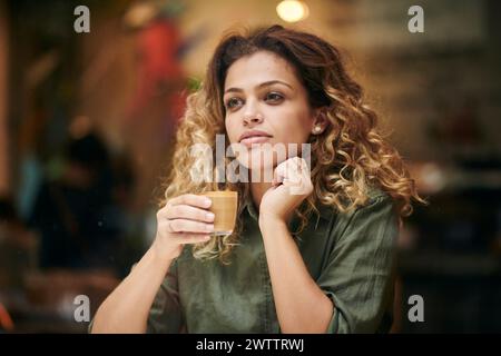 Woman holding a cup of coffee looking thoughtful. Stock Photo