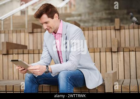 Man sitting on steps using a tablet Stock Photo